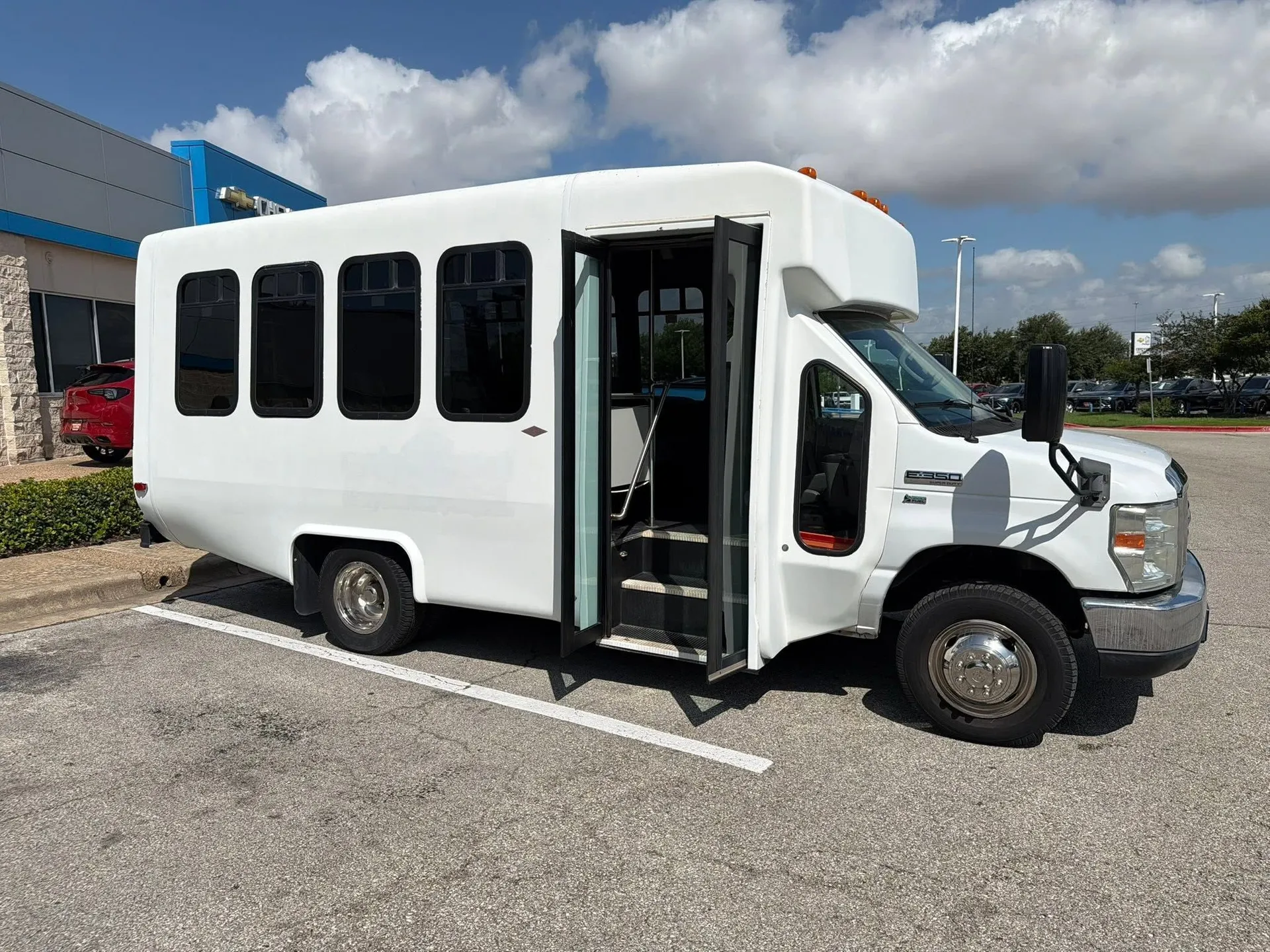 Real 15-Passenger High-Roof E-350 with the passenger door open in a sunlit commercial lot