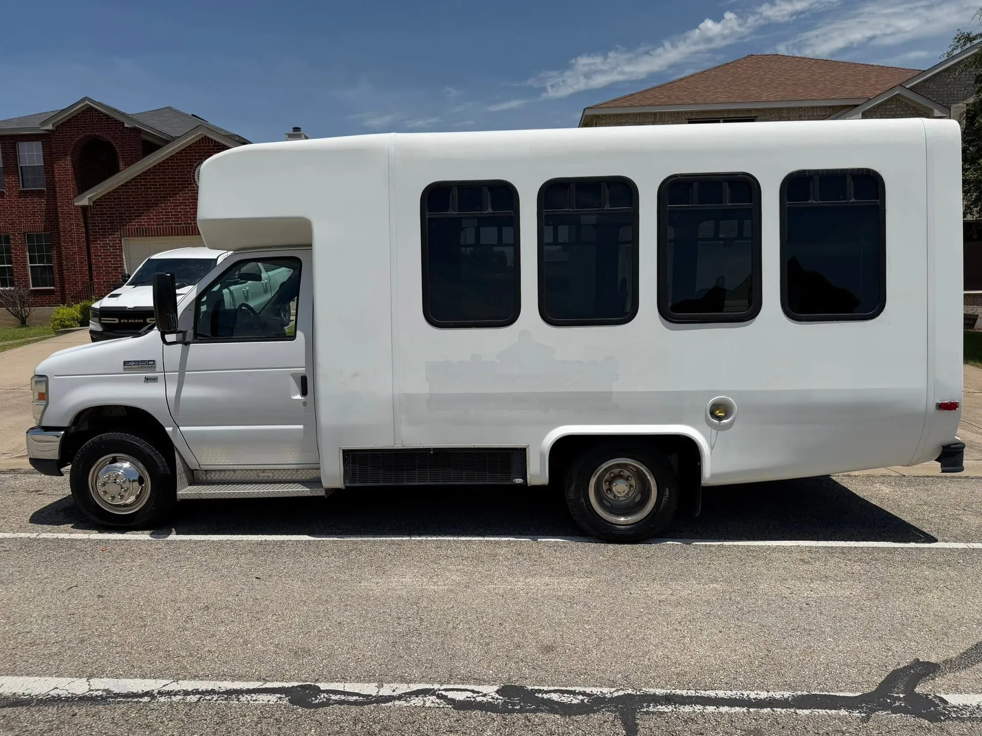 Real 15-Passenger High-Roof E-350 in side profile on a sunny residential street for passenger group travel